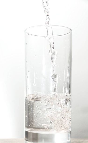 Vierta el agua en vidrio aislado sobre fondo blanco con el camino de recorte. - Foto, Imagen