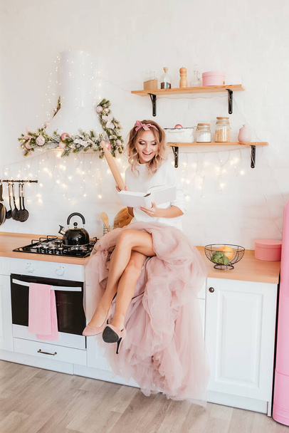パフィードレスとセーターの明るいピンクのキッチンで若い美しいブロンドの女の子。新年のコンセプトは、パーティーの準備。高品質の写真 - 写真・画像
