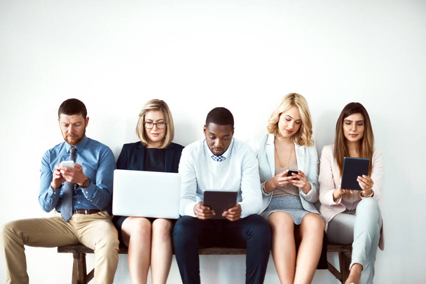 He elävät teknologialle. ryhmä työtovereita, jotka istuvat vierekkäin ja käyttävät elektronisia laitteita valkoisella taustalla - Valokuva, kuva