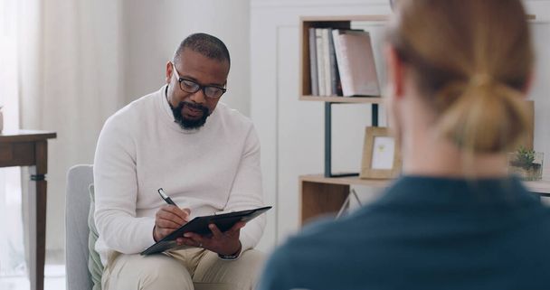 Black man, psychology and writing note with woman patient in counseling appointment for help, support and consulting. Psychologist listening, advice and helping client with mental health or anxiety. - Photo, Image