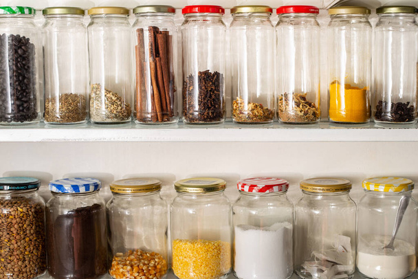 Vista frontal de algunos recipientes de vidrio con comida a granel en un estante de pared. Reutilización de envases de vidrio para productos industrializados. - Foto, imagen