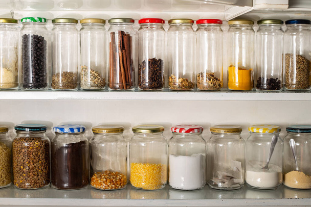 Front view of some glass containers with bulk food on a wall shelf. Reuse of glass packaging for industrialized products. - Photo, Image