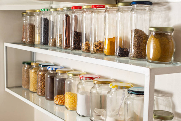 Vista lateral de algunos recipientes de vidrio con comida a granel en un estante de pared. Reutilización de envases de vidrio para productos industrializados. - Foto, Imagen