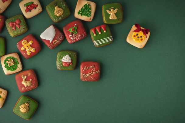 Pyszne ciasteczko świąteczne z kalendarza adwentowego, aby odliczyć dni w oczekiwaniu na Boże Narodzenie. Piernikowe ciasteczko z świątecznym lukrem na zielonym tle. Wesołych Świąt i Szczęśliwego Nowego Roku - Zdjęcie, obraz