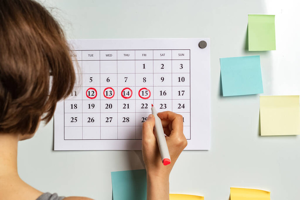 Das Konzept des Menstruationszyklus, Eisprungzeit. Die Frau markiert die Tage im Kalender. - Foto, Bild