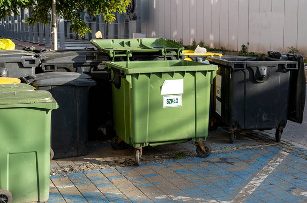 Schwarze, blaue, gelbe, grüne Mülltonnen auf den Straßen der Stadt. Müll trennen, das Umweltkonzept bewahren. Müll trennen, Müll trennen. Farbige Mülltonnen mit Papier, Glas, Kunststoff - Foto, Bild