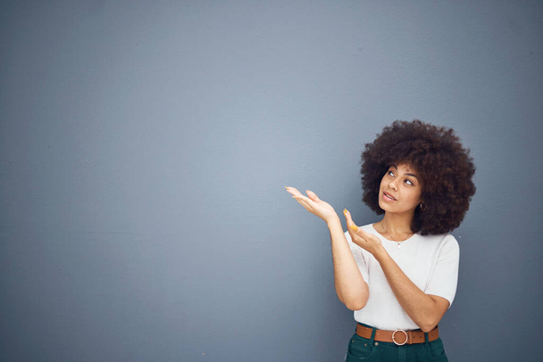 Afro kobieta, pokazując ręce i przestrzeń reklamową na szarym tle studio do marketingu makiety, kreatywne oferty lub makiety projektowania. Brazylijski model, wskazywanie i promocja na szarym tle dla marki. - Zdjęcie, obraz
