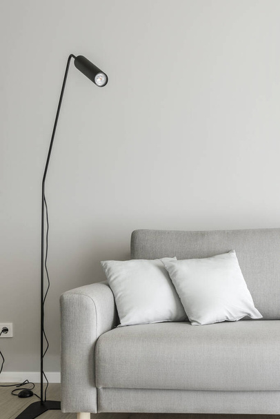 Moderní minimalistický interiér obývacího pokoje s šedou pohovkou, koženým sedadlem, černou elegantní lampou. Estetická jednoduchá koncepce interiérového designu. - Fotografie, Obrázek