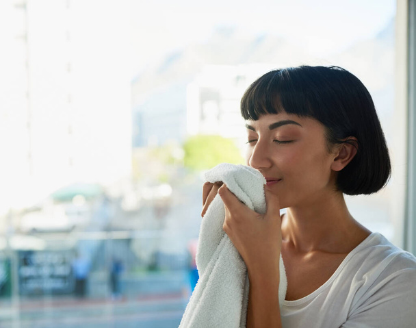 Обожаю запах чистого белья. Молодая женщина нюхает свежие полотенца дома - Фото, изображение
