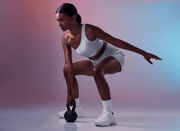 Fitness, kettlebell and woman training in studio for full body balance, powerful muscles and strong arms. Sports, exercise and healthy Indian girl swinging weights or weightlifting in a squat pose. - Fotó, kép