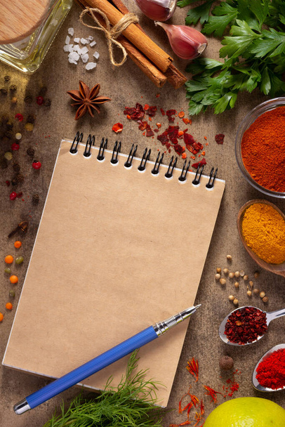 Cookbook and variety of spices and herbs on table background. Cooking concept and ingredients top view - Fotó, kép