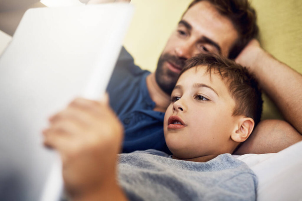 Przeczytajmy jeszcze jeden, tato. młody człowiek korzystający z tabletu cyfrowego ze swoim synem w domu - Zdjęcie, obraz