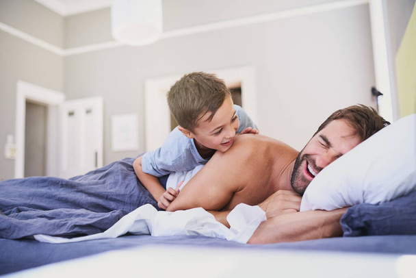 Its late already...a handsome young man being woken up by his son - Photo, Image