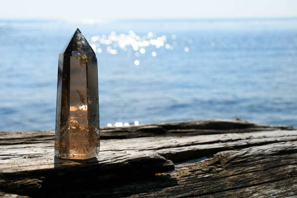 Una imagen de una torre de cristal de cuarzo ahumado alto con el océano azul brillante detrás de él. - Foto, imagen