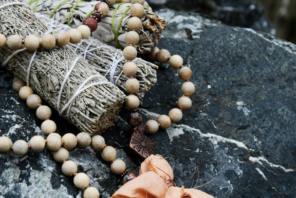 木のビーズで作られたマラの祈りのネックレスと癒しのスマッジスティックのイメージ.  - 写真・画像