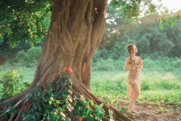 Nostalginen teema, tyttö soittaa huilua puun alla - Valokuva, kuva