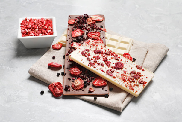 Different chocolate bars with freeze dried fruits on grey marble table - Valokuva, kuva
