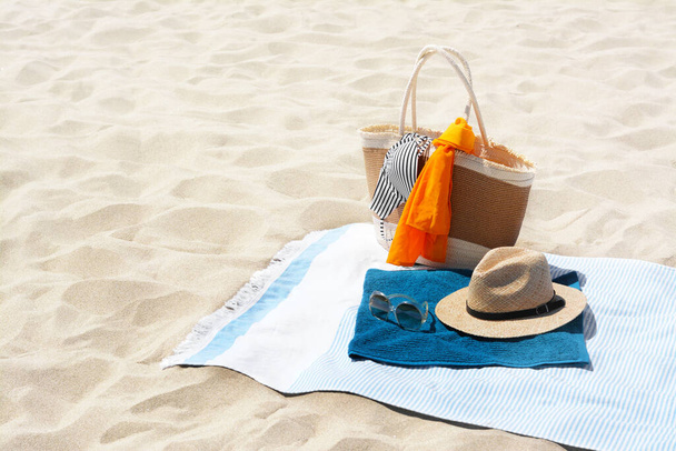 Blue blanket with towel, bag and beach accessories on sand. Space for text - Photo, image