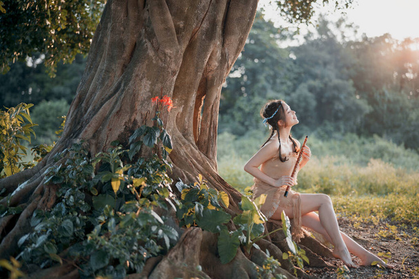 Nostalgic theme, girl playing flute under tree - Valokuva, kuva