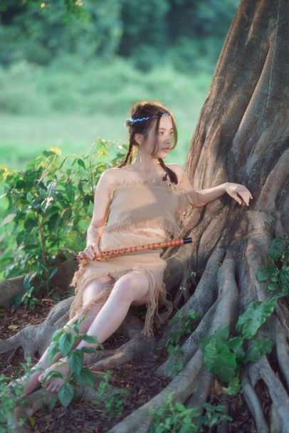 nostalgic theme, girl playing flute under tree - Foto, Imagen