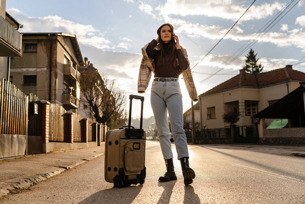 One Woman young adult female with suitcase walking on the street moving to new house tourist lost in the evening searching for apartment or hotel for accommodation leaving town real people copy space - Foto, Bild