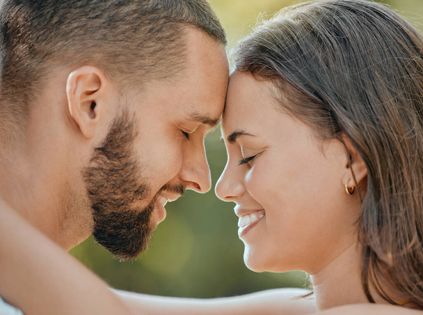 Couple, forehead and hug with smile for love, romance or embracing relationship together in the outdoors. Happy man and woman touching foreheads and hugging in happiness for loving affection outside. - 写真・画像