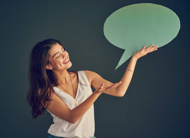 My thoughts agree with what Im saying. Studio shot of a cheerful young woman holding up a speech bubble while standing against a dark background - 写真・画像