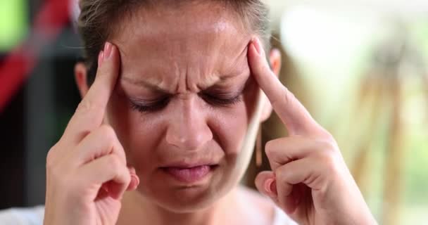 Bir kadın şakak parmaklarına masaj yapar, yakın plan bir yüz, yavaş çekim. Kavramsal baş ağrısı, stresli durum - Video, Çekim