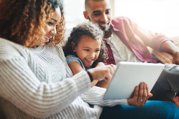 Es ist Zeit, etwas über Technologie zu lernen. ein entzückendes kleines Mädchen und ihre Eltern mit einem digitalen Tablet zusammen auf dem heimischen Sofa - Foto, Bild