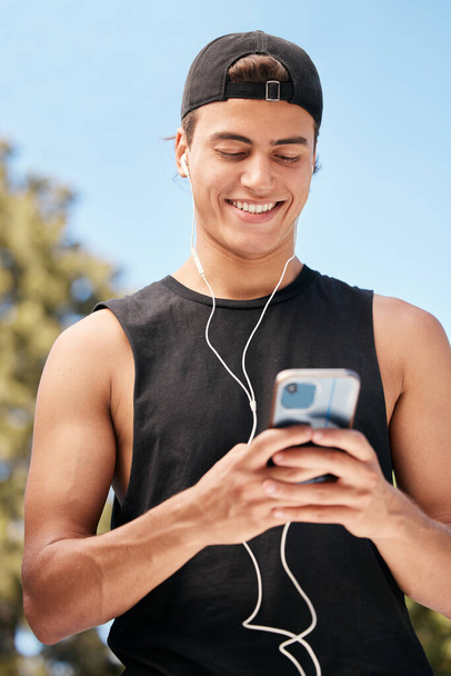 Fitness, phone and man on social media for a meme, internet entertainment or trending online content outdoors. Smile, happy and healthy athlete texting, posting or typing a funny message on cool app. - Photo, Image