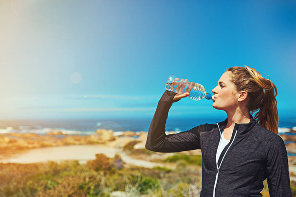 Apaga la sed de seguir ejercitándote. una joven deportista bebiendo agua al aire libre - Foto, Imagen