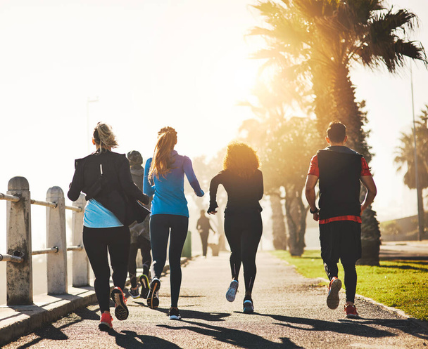 Your health depends on it. Rearview shot of a fitness group out running on the promenade - Foto, Imagem
