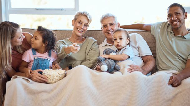 Happy family on sofa watching tv with popcorn and kids show, film or comedy movie on live streaming service. Television, relax and grandparents with children on couch with love, diversity and talking. - Φωτογραφία, εικόνα
