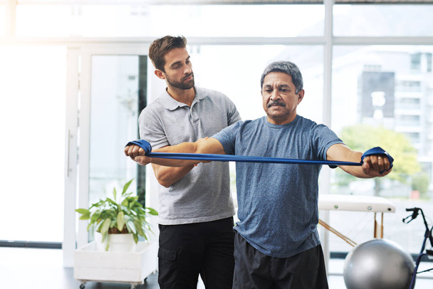 Bleiben Sie einfach ein bisschen so. ein junger männlicher Physiotherapeut hilft einem älteren männlichen Patienten mit Bewegungsübungen in einer Klinik - Foto, Bild