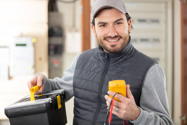 portrait of male electrician holding toolbox and multimeter - Photo, image