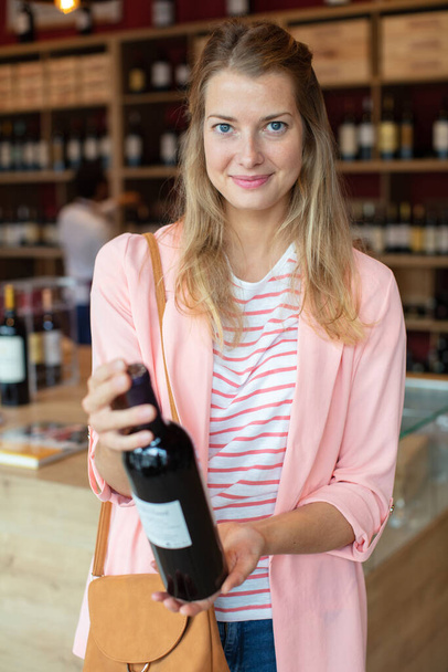 woman trying to decide which bottle of wine to buy - Zdjęcie, obraz