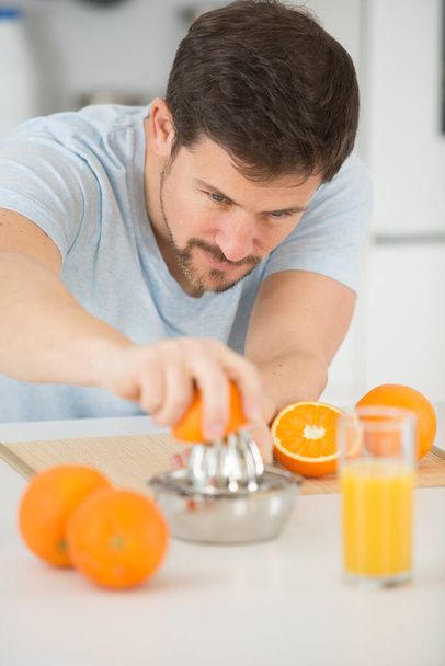 man making orange juice in the kitchen - Фото, изображение