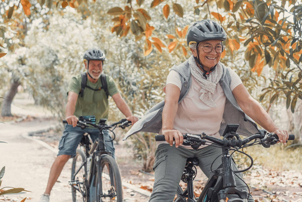 Dwoje szczęśliwych, dojrzałych ludzi, cieszących się razem i jeżdżących na rowerach, aby być zdrowymi i zdrowymi na świeżym powietrzu. Aktywni seniorzy dobrze się bawią na łonie natury.  - Zdjęcie, obraz
