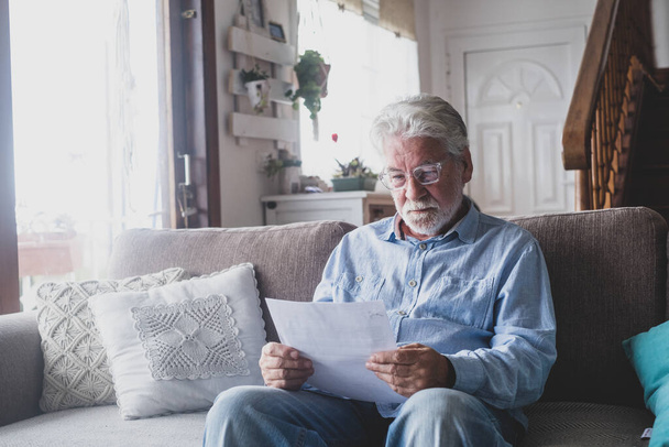 健康保険契約を読んでいる悲しい高齢者は、医療結果を見て読んで閉じます.専門家との銀行契約で悪い病気成熟したシニア感。家での結果の確認.  - 写真・画像