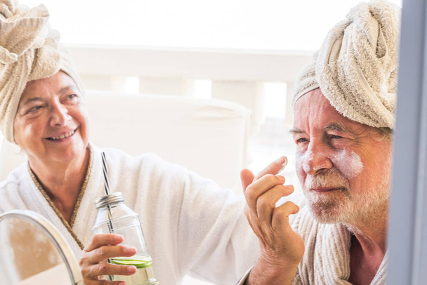 két idős vagy érett ember, akik együtt isznak vagy koktéloznak otthon vagy egy hotelben masszázs kezelés alatt  - Fotó, kép