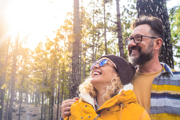 portrait of couple of two happy people looking at the trees in the forest and enjoying together the nature outdoors  - Photo, Image