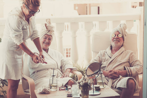 Paar von zwei gesunden und glücklichen Senioren, die eine Massage und Behandlung mit einem Assistenten genießen  - Foto, Bild