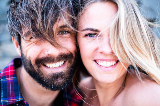 close up portrait of beautiful and handsome man and woman together with their faces near each other, looking at the camera and smiling - blonde woman with blue eyes and handsome man with green eyes - Photo, Image