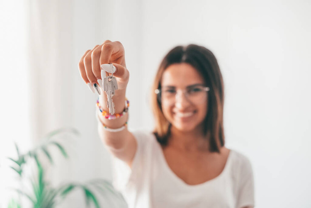 Real estate agent holding keys to new apartment. Portrait of attractive young caucasian woman with short hair holding new house keys. Young female homeowner showing keys.  - Foto, afbeelding