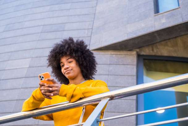 Şehrin sokaklarında milenyum melez kızı. Pozitif genç Afro-Amerikan kadın web sörfü, bilgi arama, açık havada online alışveriş  - Fotoğraf, Görsel