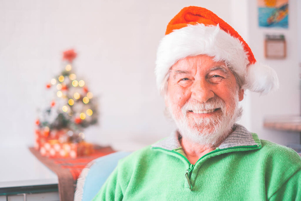 Портрет усміхненого старшого чоловіка на пенсії у Санта-Хаті та теплий одяг, що відзначає Різдво вдома. Старий Миколай посміхається, дивлячись на камеру. Літній чоловік отримує різдвяну відпустку.  - Фото, зображення