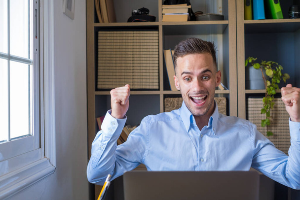 Overjoyed caucasian ethnicity man sit at desk looks at laptop screen read incredible news clench fists makes yes gesture celebrate on-line lottery gambling win, getting new job offer feels happy  - Fotó, kép