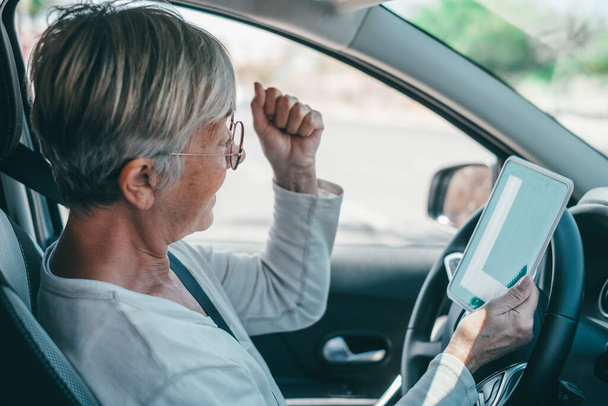 Eine alte Frau bekommt die Erlaubnis, im reifen Alter Auto zu fahren. Senior blickt auf L-Kennzeichen im Fahrersitz und feiert den Erfolg  - Foto, Bild