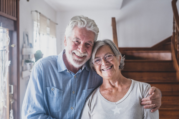 Portret van gelukkig paar oude mensen senioren knuffelen elkaar, kijken naar de camera, liefde voor volwassen vrouw en man met een gezonde speelse glimlach poseren om familiefoto thuis.   - Foto, afbeelding