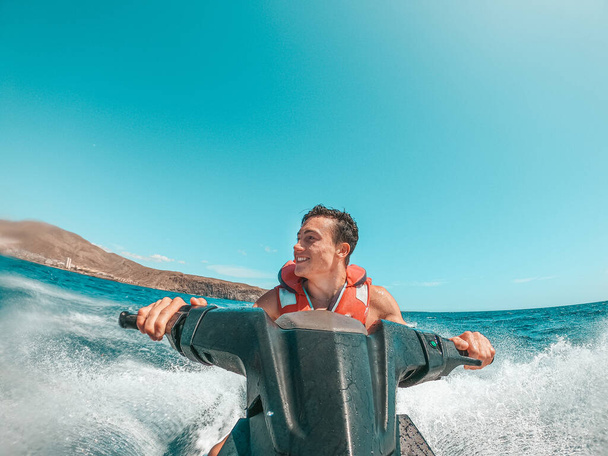 Tiener man genieten van de zomer in een jet ski in het midden van de zee plezier hebben racen alleen en geïsoleerd.  - Foto, afbeelding